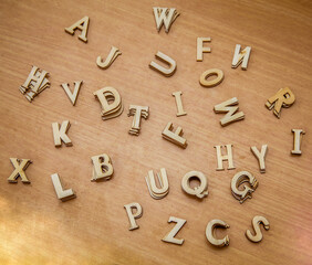 Wooden letters of the English alphabet lie on a wooden surface
