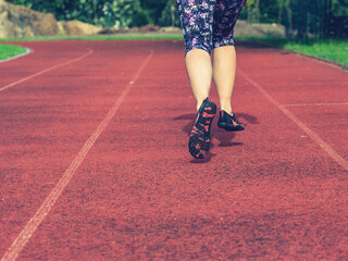 Mature asian woman in flowered up knees leggings  running along track
