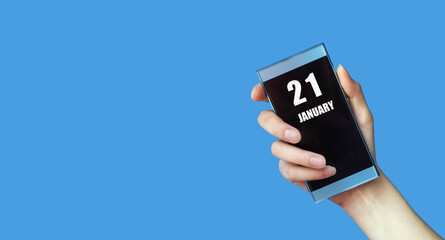 january 21. 21th day of the month, calendar date.Woman's hand holds mobile phone with blank screen on blue isolated background.Winter month, day of the year concept