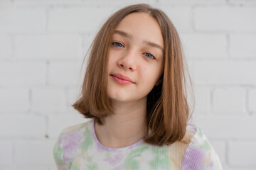 portrait of a slender teenage girl in a light turtleneck in natural light against a white brick wall. natural beauty, no makeup. problematic skin. space for text. High quality photo