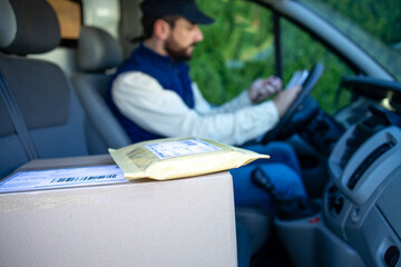 Close up view on package shipment and delivery man driver filling papers in his van.