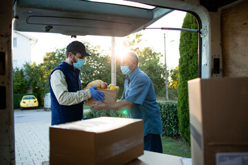 Senior man accepting food delivery from deliveryman during covid19 pandemic or lockdown.