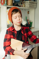 boy in a red hat and a plaid shirt plays the balalaika. Handsome boy holding his guitar. Music...