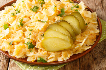 European food Pasta with potatoes and onions served with pickles close-up in a plate on the table. horizontal