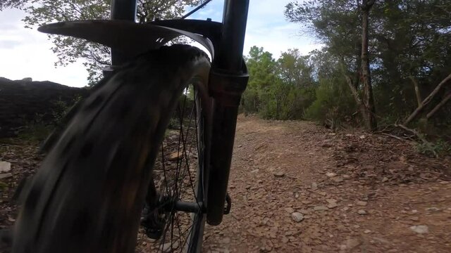 Front mountain bike wheel perspective riding on a rock trail downhill