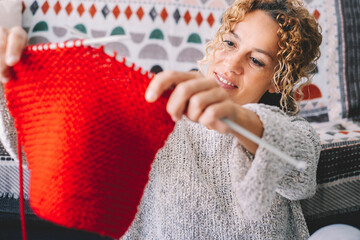 Adult attractive woman at home in knitting work activity using colorful wool. Happy and relaxed...