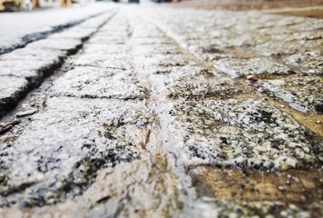 Sidewalk made of old cobblestone that was rainy from the previous evening.  The alignment of the...