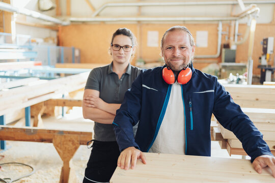 Smiling carpenter with female colleague in a woodworking factory