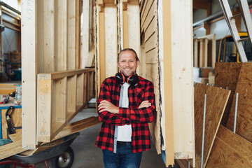 Confident smiling carpenter leaning against prefabricated walls