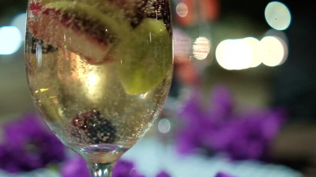 Bubbly dink with fruit slices in wine glass with blurry background