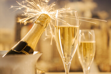 Two champagne glasses and a bottle with a sparkle on the top of it