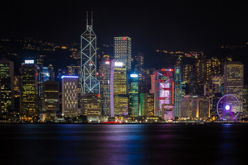 Hong Kong City skyline with tourist sailboat at night. View from across Victoria Harbor HongKong.