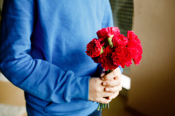 Closeup of hands of preteen kid boy holding bunch of clove flowers. Child congrats and presents cloves to mother or girl friend for mothers day or valentines day.
