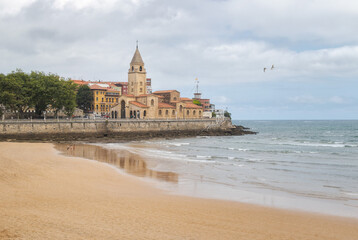 Walk along the beach of San Lorenzo next to the church of San Pedro in Gijón, Asturias, Spain.