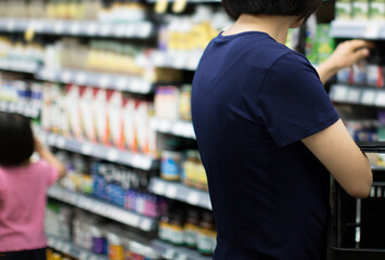 Female customer choosing product at pharmacy. Woman in pharmacy drugstore. 
Consumer shopper at store aisle shopping for vitamins, supplements, drugs, 
medicine, pills. Healthcare concept.
