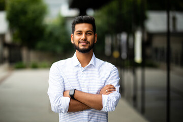Handsome smiling indian young man with folded arms. Portrait of laughing joyful cheerful men with...