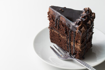 Slice of chocolate cake on white background with cake fork and space for text