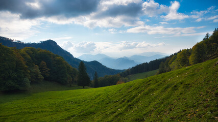 Landschaftsaufnahme mit Bergen, einer Almweise und blauem Himmel mit Wolken