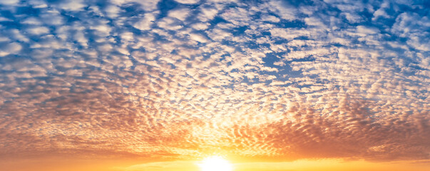 The bright sunrise and fluffy clouds full on blue sky, panorama nature picture.