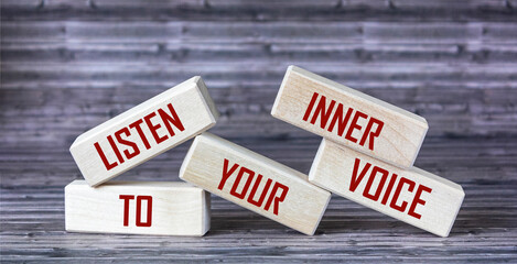 Listen to your inner voice - the text is written on wooden blocks that lie on a wooden background. - obrazy, fototapety, plakaty