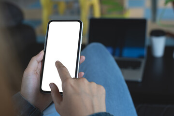 Cell phone mockup image blank white screen. Woman hand holding, using mobile phone during working on laptop computer at coffee shop. empty space for advertise text.