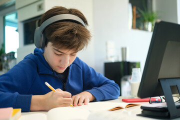 Naklejka na ściany i meble Student boy with tablet computer learning at home.