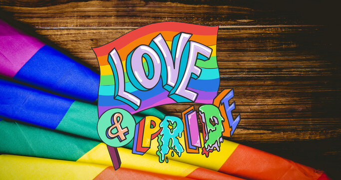 Image of rainbow love and pride over rainbow lying on wooden background