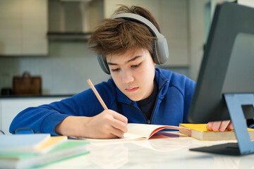 Naklejka na ściany i meble Student boy with tablet computer learning at home.