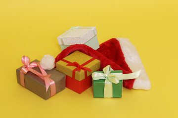 Four boxes with presents and Santa hat on yellow paper background.