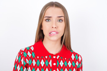 Young caucasian girl wearing christmas sweaters on white background being nervous and scared biting lips looking camera with impatient expression, pensive.