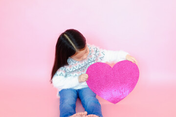 Portrait beautiful cute asian child girl on pink background with red heart sign, valentine day in love concept