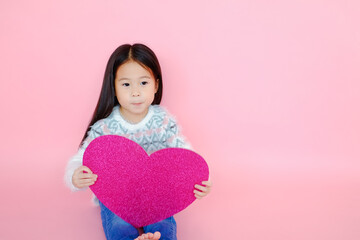 Portrait beautiful cute asian child girl on pink background with red heart sign, valentine day in love concept