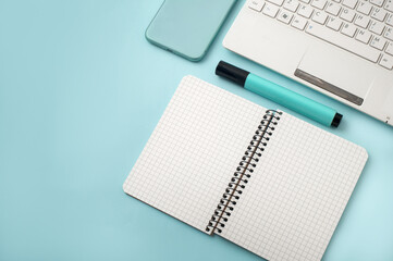 Top view of the blue desk with notebook, notebook, stationery and telephone.
