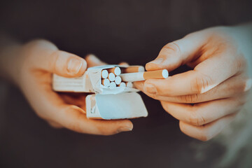 A man holds an open pack of cigarettes in his hands and takes a cigarette out of it to light it. Nicotine addiction. The habit of smoking.