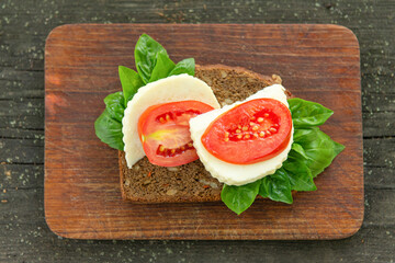 Sandwiches for breakfast, snack, cheese whole grain bread sandwiches tomato and basil on an old dark wooden background