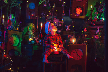 A happy boy-child is in the New Year decorations. A child in Christmas pajamas.