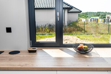 Large corner window in a modern kitchen with built-in cabinets against the wall with white fronts.