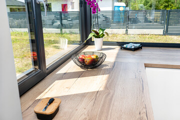 Large corner window in a modern kitchen with built-in cabinets against the wall with white fronts.