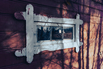 Routed window on an old wall with shadows from trees.