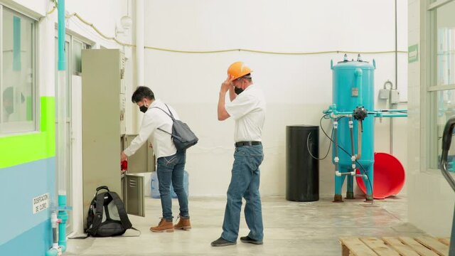 Workers putting on coveralls in locker room