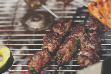 closeup on fresh kofta lamb meat spits with mint that are grilled on a charcoal grill - matte...