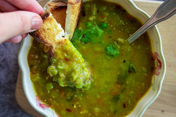 Eating Homemade pea soup with toasted bread or croutons. Green split pea soup rich in flavors,...