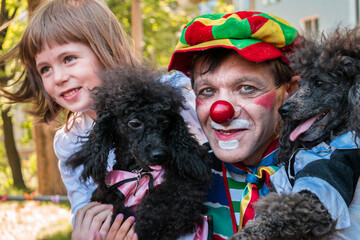 Portrait of a street clown with two dogs and a child. Selective focus