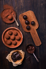 Tasty dark chocolate truffles with cocoa dusting on a brown background
