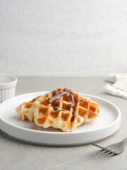 Croissant Waffle or Croffle with chocolate and strawberry topping on grey background. Selective focus image and close up.
