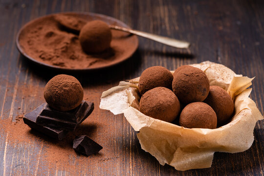 Tasty dark chocolate truffles with cocoa dusting on a brown background