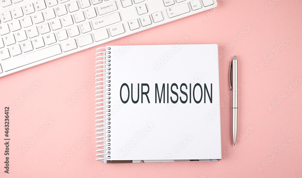 Poster pink office desk with keyboard and notebook with text our mission