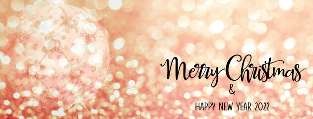 Christmas bauble against a backdrop with bokeh and glitter effect. Merry Christmas and Happy New Year quote.