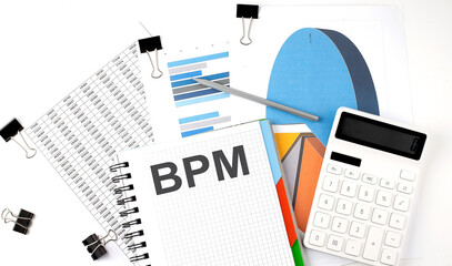 Text BPM on a notebook on the diagram and charts with calculator and pen