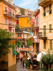 Fototapeta na wymiar Charming colourful houses overlook the street and alley in Manarola a picturesque village in the Cinque Terre, Italy. This famous UNESCO site is popular with tourists